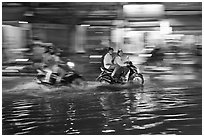 Motorcycles riding through the water on street with motion. Ho Chi Minh City, Vietnam (black and white)