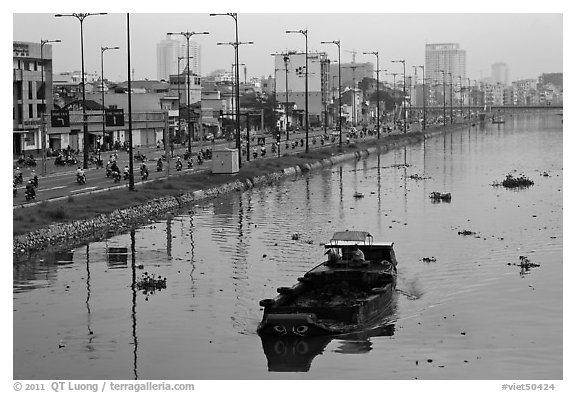 Barge with traditional painted eyes on Saigon Arroyau with backdrop of expressway traffic. Cholon, Ho Chi Minh City, Vietnam (black and white)