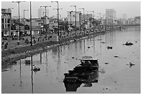 Barge with traditional painted eyes on Saigon Arroyau with backdrop of expressway traffic. Cholon, Ho Chi Minh City, Vietnam (black and white)