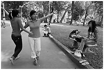 Young women dancing to sound of mobile phone, Tao Dan Park. Ho Chi Minh City, Vietnam ( black and white)