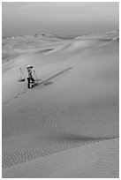 Rippled red sand dunes and woman with baskets. Mui Ne, Vietnam (black and white)