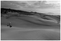 Coastal sand dunes with sea in distance and local woman. Mui Ne, Vietnam (black and white)