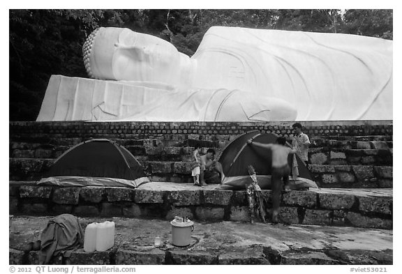 Pilgrims pitch tent below reclining Buddha statue. Ta Cu Mountain, Vietnam