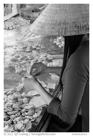 Woman wearing conical hat wrapping coconut candy, Phoenix Island. My Tho, Vietnam (black and white)
