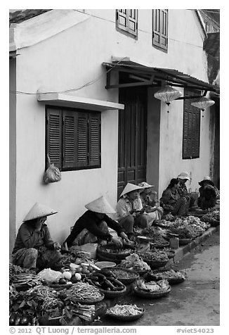 Vegetable vendors sitting in front of old house. Hoi An, Vietnam (black and white)