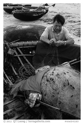 Fisherman repairing net on beach. Da Nang, Vietnam