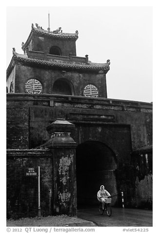 Biking through citadel gated entrance in the rain. Hue, Vietnam (black and white)
