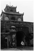 Biking through citadel gated entrance in the rain. Hue, Vietnam (black and white)