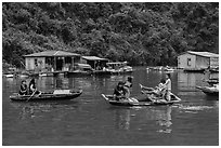 Villagers move between floating houses by rowboat. Halong Bay, Vietnam (black and white)