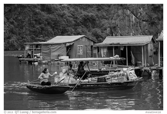 Woman buying produce from grocery boat, Vung Vieng village. Halong Bay, Vietnam