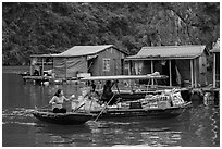 Woman buying produce from grocery boat, Vung Vieng village. Halong Bay, Vietnam (black and white)