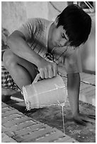 Man pouring clay into molds in ceramic workshop. Bat Trang, Vietnam (black and white)