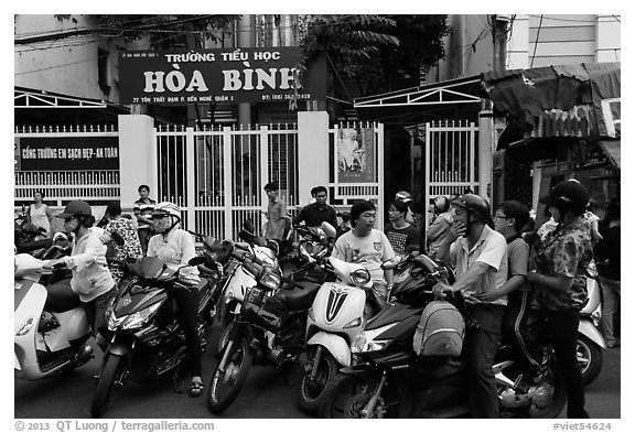 School entrance with parents waiting on motorbikes. Ho Chi Minh City, Vietnam (black and white)