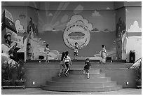 Children on stage next to militaristic mural, Dam Sen Water Park, district 11. Ho Chi Minh City, Vietnam (black and white)