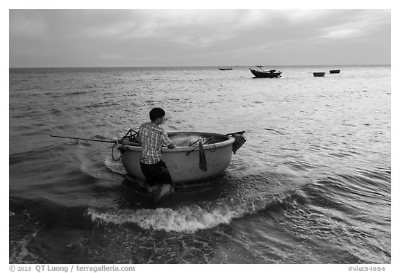 Man holding coracle boat. Mui Ne, Vietnam