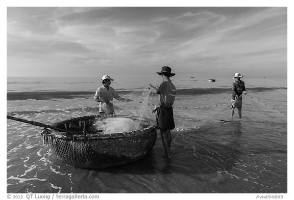 Fishermen folding fishing net into coracle boat. Mui Ne, Vietnam