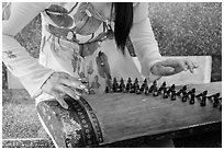 Close up of hands playing plucked zither. My Tho, Vietnam (black and white)