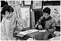 Caligrapher draws Tet greetings as woman looks on. Ho Chi Minh City, Vietnam ( black and white)