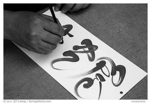 Hands drawing Tet (Lunar New Year) greetings in Chinese characters. Ho Chi Minh City, Vietnam (black and white)