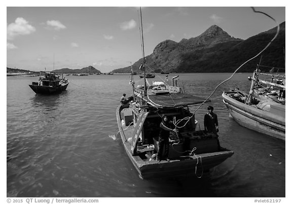 Sailor throws rope from boat, Ben Dam harbor. Con Dao Islands, Vietnam (black and white)