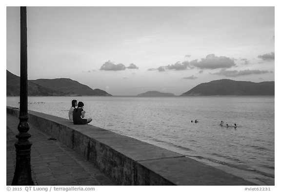 Young women sitting on seawall, evening, Con Son. Con Dao Islands, Vietnam (black and white)