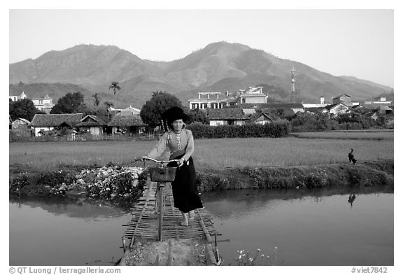 Thai woman pushing her bicycle across a bridge, Tuan Giao. Northwest Vietnam (black and white)