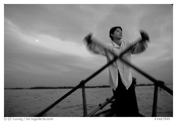 Boater using the X-shaped paddle characteristic of the Delta, sunset. Can Tho, Vietnam