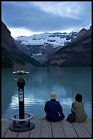 Couple sitting at the edge of Lake Louise at dawn. Banff National Park, Canadian Rockies, Alberta, Canada