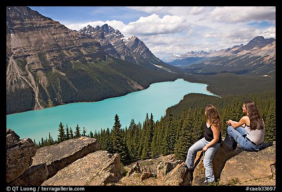 Tourists sitting on a rook overlooking Peyto Lake. Banff National Park, Canadian Rockies, Alberta, Canada (color)