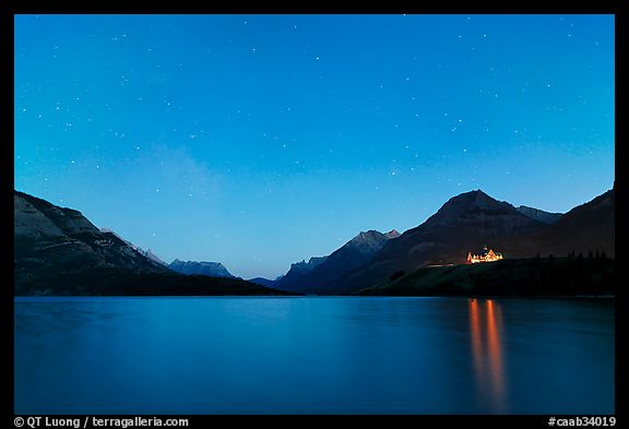 Waterton lake by night with stars in the sky in lights of Price of Wales Hotel. Waterton Lakes National Park, Alberta, Canada (color)