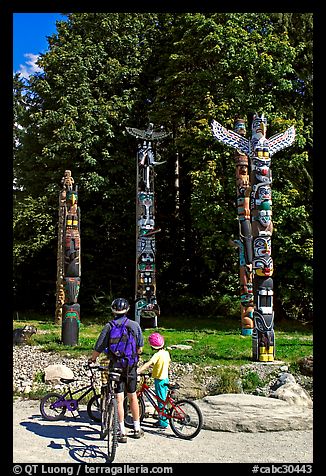 Family with bicycles looking at Totems, Stanley Park. Vancouver, British Columbia, Canada