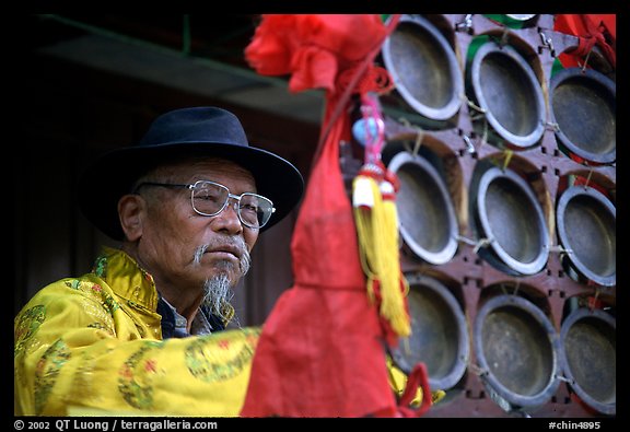 Elderly  musician playing a traditional percussion instrument. Baisha, Yunnan, China