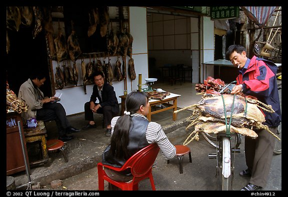 Loading roasted meat on a bicycle. Kunming, Yunnan, China