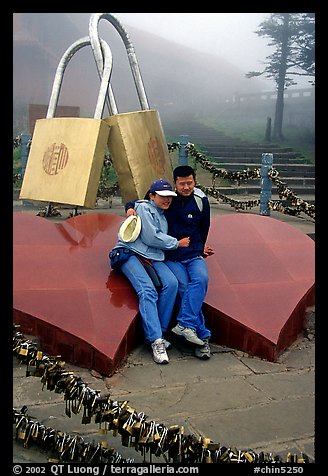 Lovers sit on top of two hearts surrounded by chain locks. Emei Shan, Sichuan, China (color)