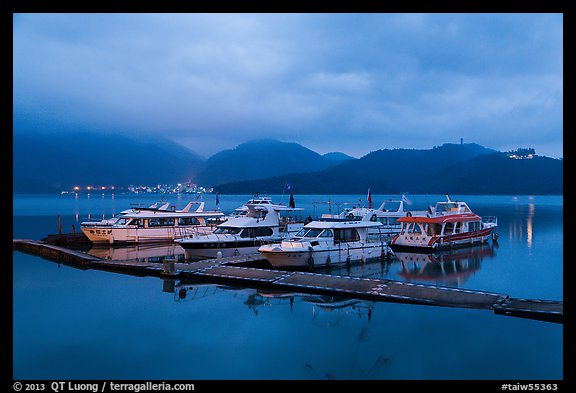 Pier with distant lights of Itashao Village and Syuanzang Temple at dawn. Sun Moon Lake, Taiwan