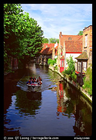 Boat on a canal lined with houses and trees. Bruges, Belgium