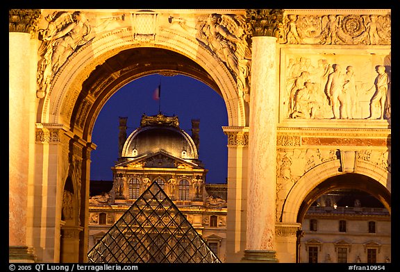 Louvre and  pyramid  seen through the Carousel triumphal arch at night. Paris, France