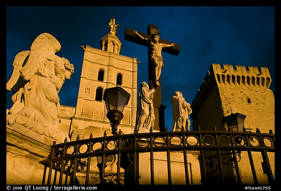 Cross with Christ, statues, and towers, evening light. Avignon, Provence, France
