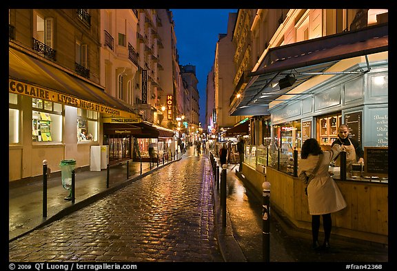 Woman buying food on street at night. Quartier Latin, Paris, France