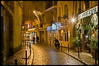 Street with cobblestone pavement and restaurants by night. Quartier Latin, Paris, France (color)
