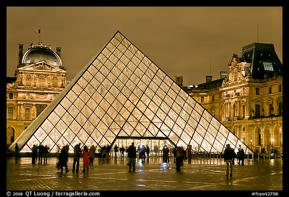 People standing in front of Louvre Pyramid by night. Paris, France