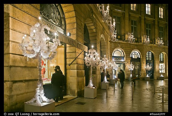 Looking at the storefronts of luxury stores at night, Place Vendome. Paris, France