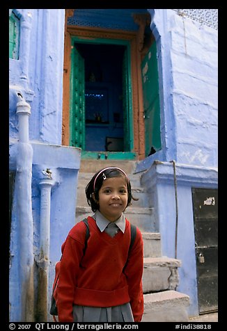 Schoolgirl standing in front of a house with blue tint. Jodhpur, Rajasthan, India