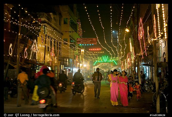 Women walking in street with illuminations. Varanasi, Uttar Pradesh, India (color)