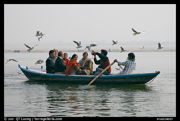 Indian tourists on rawboat surrounded by birds. Varanasi, Uttar Pradesh, India