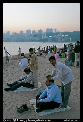 Head masseurs and Mumbai skyline at sunset,  Chowpatty Beach. Mumbai, Maharashtra, India