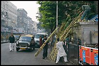 Men loading sugar cane on a street booth. Mumbai, Maharashtra, India (color)