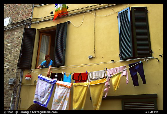 Woman hanging laundry. Siena, Tuscany, Italy