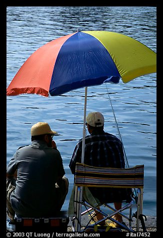 Men fishing under an colorful sun unbrella,  Agropoli. Campania, Italy