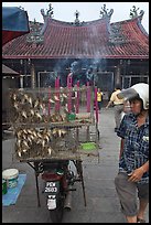 Motorcycle loaded with cage of birds (to be freed) in front of temple. George Town, Penang, Malaysia (color)